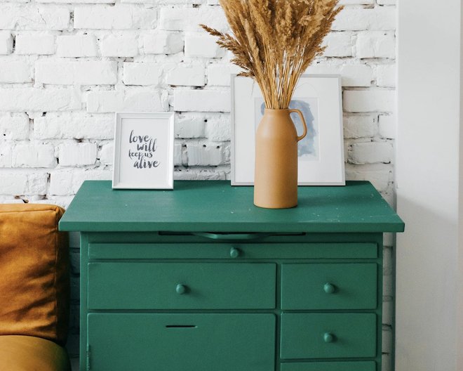 chest of drawers with a vase and two photo frames on top